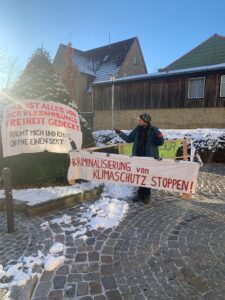 Mensch mit Gehzeug mit Schild "Kriminalisierung von Klimaschutz stoppen"